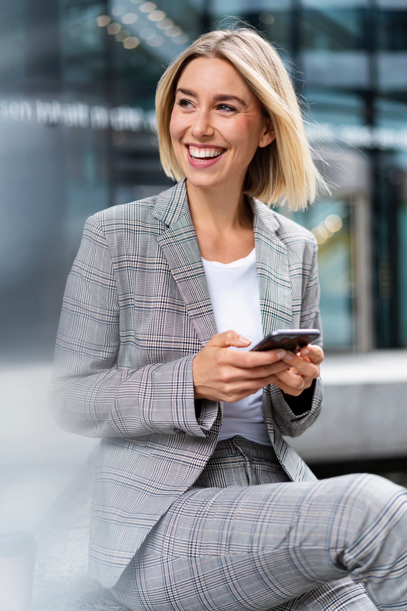 Happy young businesswoman with mobile phone in the city